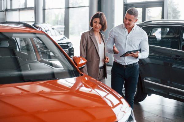 With notepad. Man in formal wear helping customer with choice of the automobile.